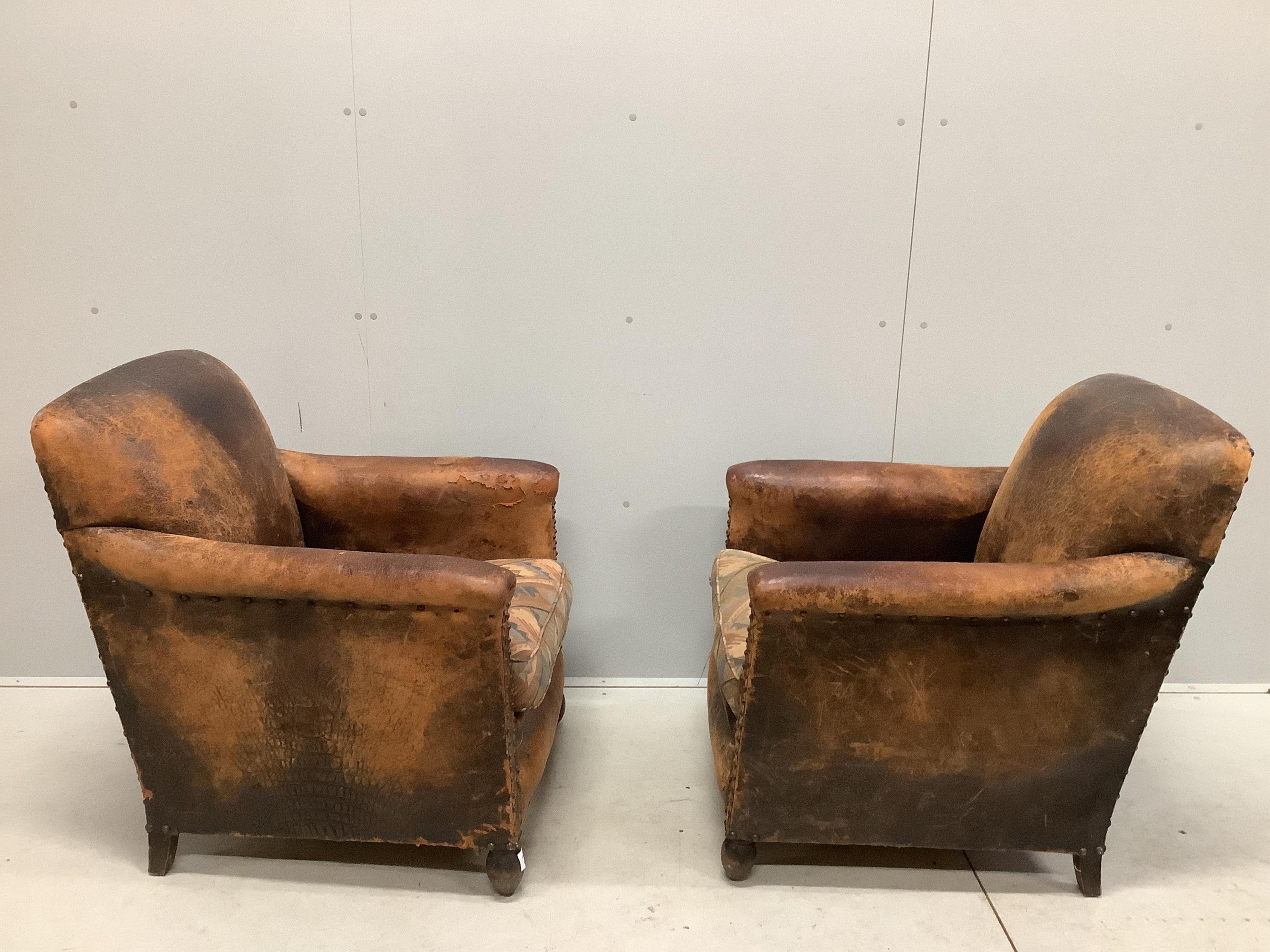 A pair of early 20th century French leather club armchairs, width 73cm, depth 74cm, height 83cm. Condition - poor to fair